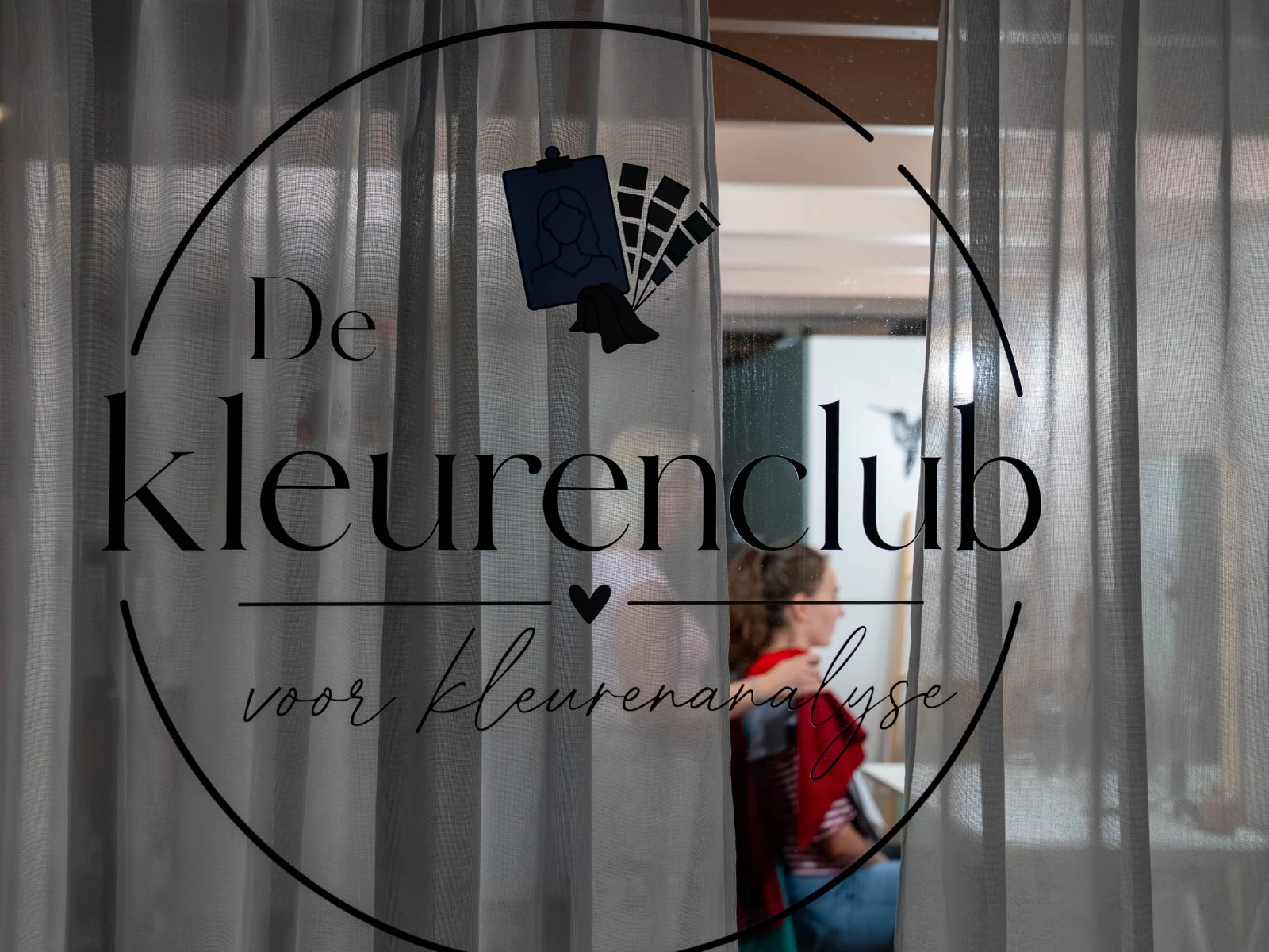 Het raam van de studio met het logo van De Kleurenclub